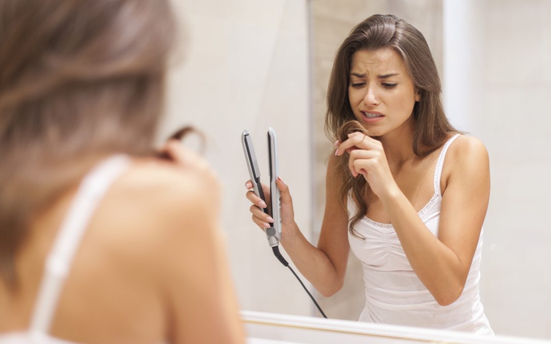 woman straightening hair in bathroom